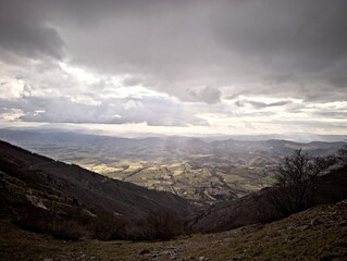 Paesaggio montano, campi coltivati e fiume nella valle illuminata dal sole