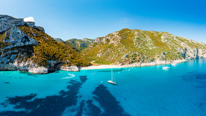 Naklejka premium Aerial view of Cala Sisine, beautiful sandy beach with turquoise water and limestone mountains along the Baunei Coast, Gulf of Orosei, Sardinia, Italy.
