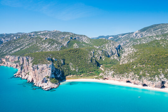 Aerial view of Cala Luna beach on the coast of Baunei and Dorgali, Sardinia, Italy. Turquoise water, white sandy shoreline and dramatic limestone cliffs along the Gulf of Orosei.