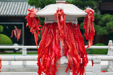 Red Blessing Ribbons on Temple Stone Structure in Asian Garden