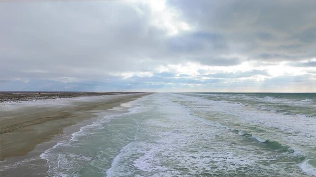 Caspian Sea sandy coastline near Aktau resort, Mangystau region, Kazakhstan, captured in a cinematic aerial drone footage showing powerful winter waves crashing onto an empty beach during the off-seas