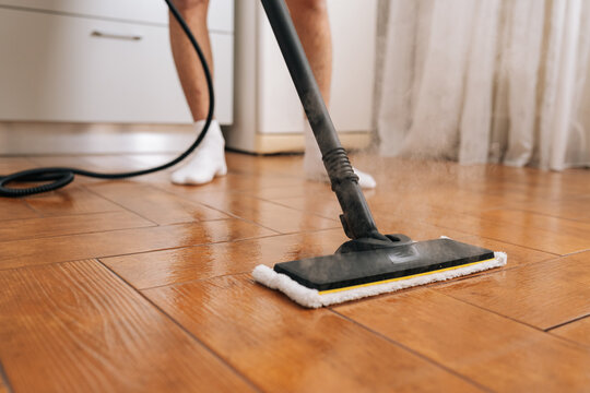 Person cleaning home floor using steam mop, sanitizing surfaces and maintaining hygiene, performing household chores for a spotless and sterile environment. Concept of cleaning and household.