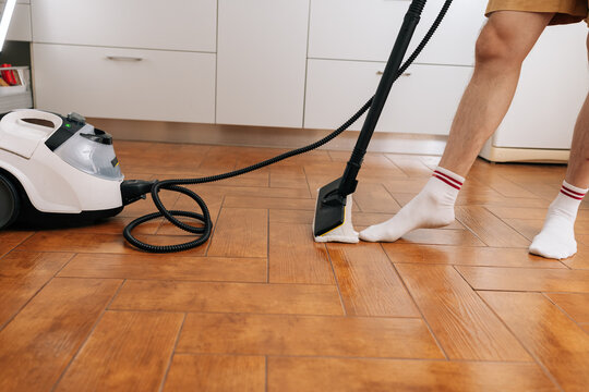 Close-up cropped shot of person using floor cleaner for home hygiene, eliminating germs and dirt from wooden floors, focusing on efficient deep cleaning and fresh living spaces.