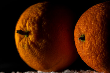 Orange fruit detail with shiny black table and white salt