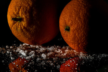 Orange fruit detail with shiny black table and white salt
