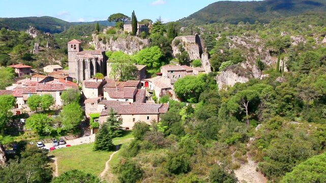 Village de Mour&egrave;ze avec ses maisons group&eacute;es autour de l'&eacute;glise et du rocher.
