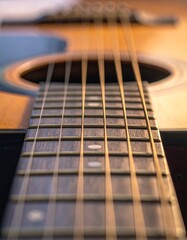 Macro shot of acoustic guitar strings and wooden fretboard with warm ambient lighting