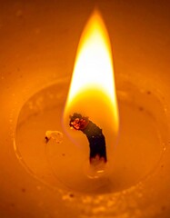 Macro shot of a single candle flame burning with a soft warm glow in the dark