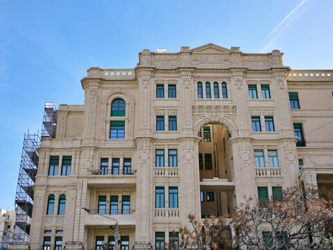 Art Nouveau facade of the iconic Balluta Buildings in St. Julian's, Malta. Ornate
limestone architecture with green shutters and scaffolding.