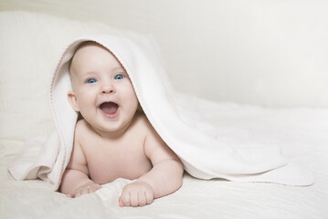 Adorable Laughing Baby Peeking from Under White Blanket with Joyful Expression