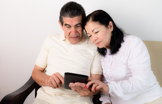 Senior couple using tablet together at home, older adults focused on digital content and modern technology.