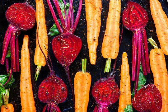 Carrots and beetroot mixed with oil and seasoning before baking. Healthy homemade vegetable preparation