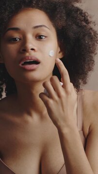 Beauty care. Mirror pov of young pretty african american woman opening jar with cream and pampering her face skin