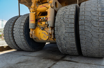 Close-up of Rear Axle and Giant Tires of a Yellow Mining Dump Truck at a mining site open pit