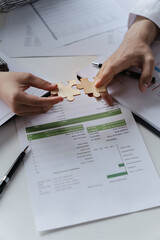 Hands interlock puzzle pieces to symbolize unity teamwork and corporate success