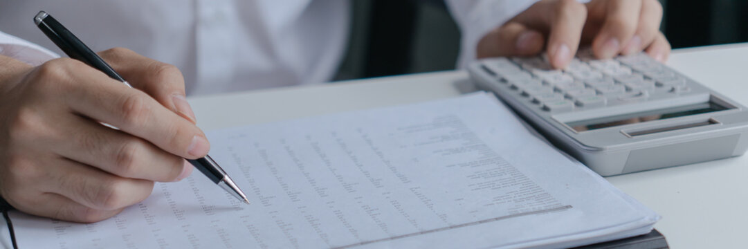financial officer checking calculator with paper documents to review business annual report in office