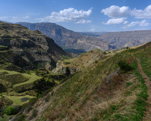 Fototapeta premium Scenic view of a mountainous canyon with green hills under a cloudy sky. Dagestan Russia.