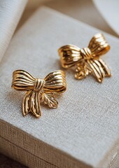 Fototapeta premium Elegant Gold Bow Earrings on Linen Box
