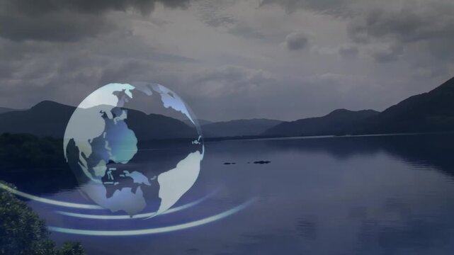 Rotating globe animation over serene lake with mountains in background