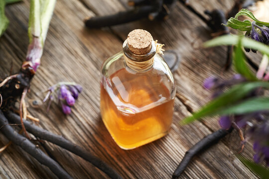 A bottle of  herbal tincture with fresh comfrey root