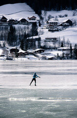 silhouette of an ice skater on a frozen Weissensee lake in winter