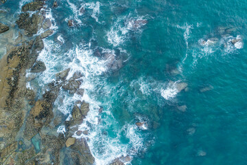 Obraz premium Aerial top down view of ocean waves crashing on rocks The Concept of Power