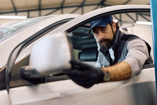 Mature mechanic examining customer's car in repair shop.