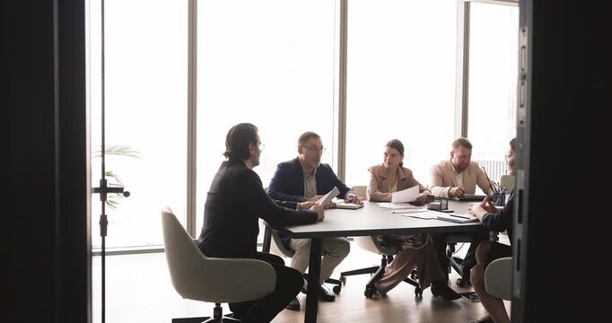 Male team leader speaking during strategic planning, partnership discussion in conference room. Group of businesspeople negotiating, collaborating on project in corporate office during formal meeting