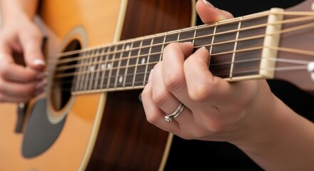 Female hands playing chords on acoustic guitar close-up