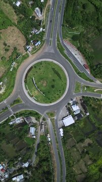 Country Intersection With Green Central Patch. View Of Rural Roundabout With Lush Surroundings. Aerial Perspective Showcasing Rural Roundabout Encircled By Vegetation And Scattered Rural Houses