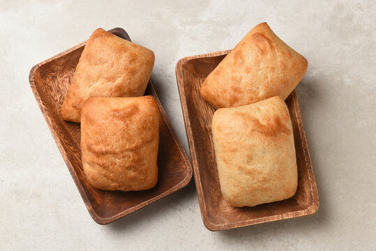 Food Still Life. High angle photograph of four Chibatta rolls on two wood plates.