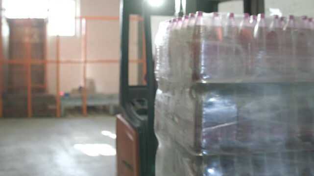 Forklift loading pallet of bottled water into a truck trailer at beverage factory.