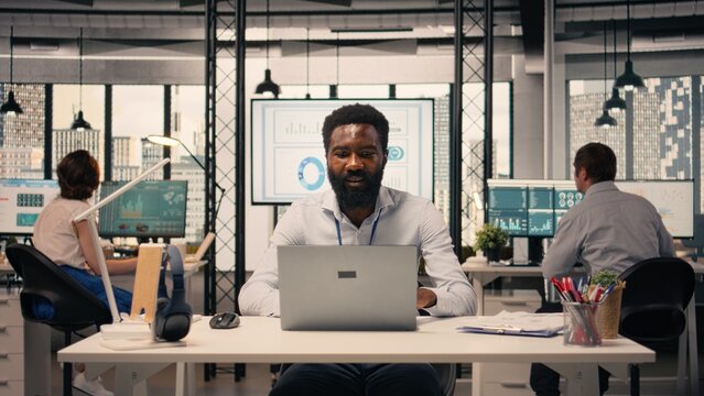 Black professional reviewing resource allocation and performance metrics on laptop. Corporate workspace with analytics dashboard supporting strategy, objectives and productivity.