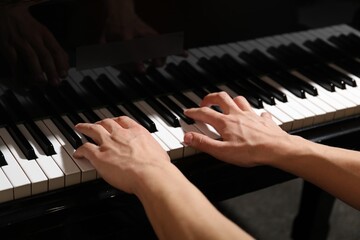 Musician playing piano indoors, closeup. Musical instrument