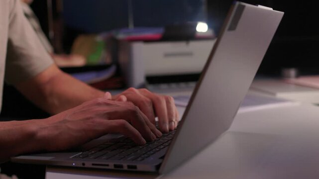 Developer working under dim light. Night coding session with glowing screen and quiet ambiance. Focused programmer typing code during late night debugging under subtle lighting