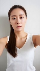 Young woman taking selfie wearing white tank top, plain casual clothing for fashion and social media