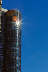 Obraz premium Sunlight reflects off a glass building in a city on a clear day with no clouds in the sky showcasing the urban landscape and architecture from a low angle view