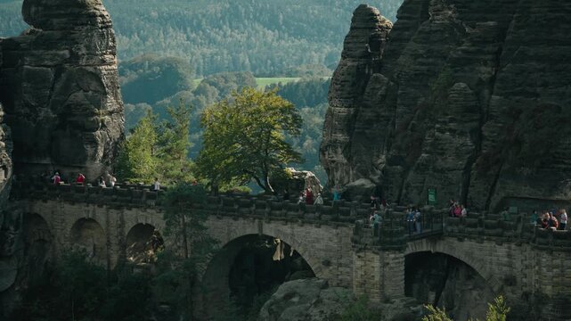a slow-motion long focal range shot of tourists walking in the famous Bastei Bridge in Saxon Switzerland, Germany in a sunny summer day