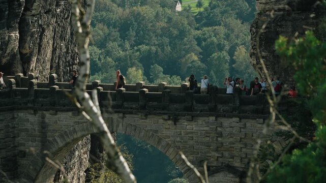 a slow-motion long focal range shot of tourists walking in the famous Bastei Bridge in Saxon Switzerland, Germany in a sunny summer day