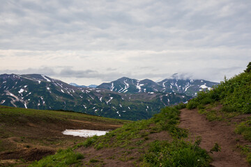Hiking trail on the mountain pass. Mountains in the distance. Summer landscape. Travel and tourism on the Kamchatka Peninsula. Beautiful nature of Siberia and the Russian Far East. Kamchatka, Russia.