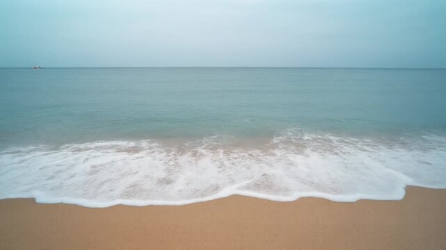 Calm Ocean Waves Gently Washing Ashore on a Sandy Beach.