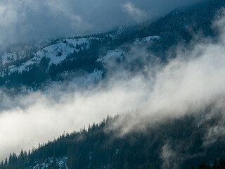 Misty Mountain Peaks Shrouded by Clouds Over Snowy Forest Slopes in Howe Sound, Canada