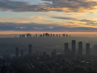Fototapeta premium Dusk City Skyline Over Foggy Burnaby, BC With Silhouetted Towers and Soft Sunrise Colors