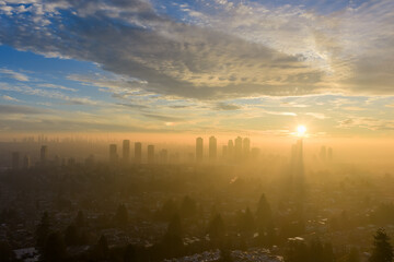 Fototapeta premium Golden Sunrise Over Burnaby Skyline With Misty Cityscape in Early Morning