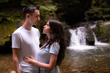 Fototapeta premium Young Couple Embracing Near Forest Waterfall