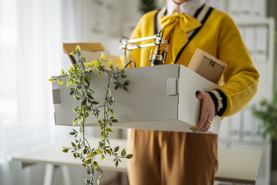Employee carrying box of personal items leaving office