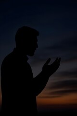 Silhouette of a Devout Muslim Man Raising Hands in Supplication and Prayer During Ramadan at Twilight