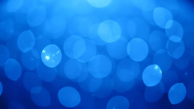 A blurry, bokeh image featuring many overlapping circles of blue light and shadow