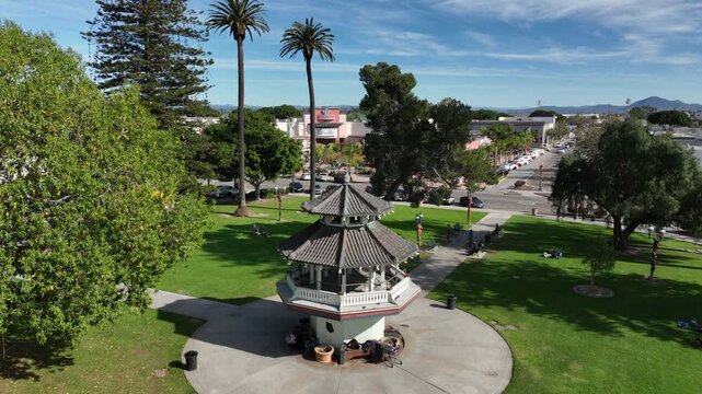 Oxnard, California, USA &ndash; Elevated Aerial View Descending Toward Plaza Park Gazebo Showing Downtown Skyline, Tree-Covered Park Area, and the Topatopa Mountains in the Background