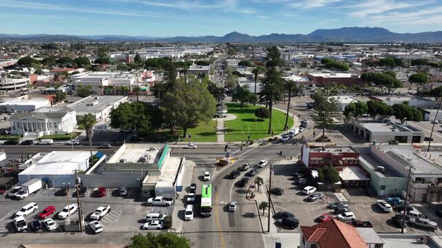 Oxnard, California, USA &ndash; Elevated Aerial View Descending Toward Plaza Park Gazebo Showing Downtown Skyline, Tree-Covered Park Area, and the Topatopa Mountains in the Background